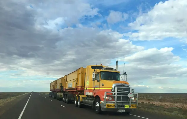 yellow road train on open highway loading=